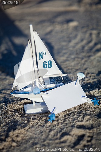 Image of sailing boat and seashell in sand decoration closeup