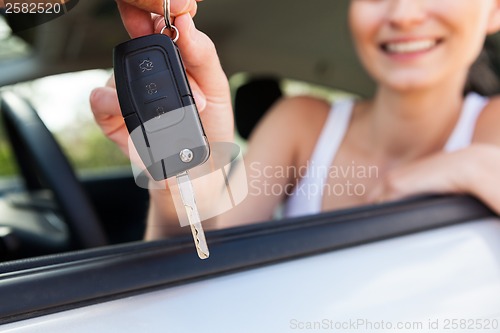 Image of young smiling woman sitting in car taking key 