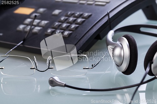 Image of working place office desk table headset glasses telephone