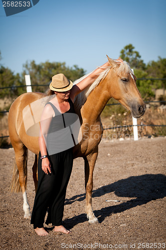 Image of young woman training horse outside in summer