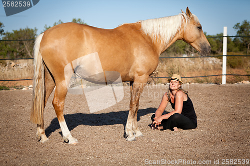 Image of young woman training horse outside in summer