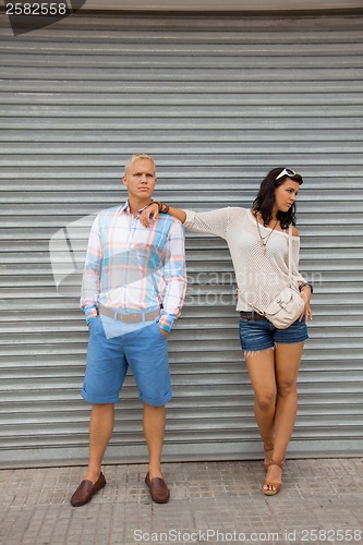 Image of Fashionable couple posing in front of a metal door