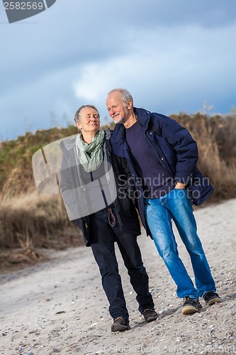 Image of happy elderly senior couple walking on beach