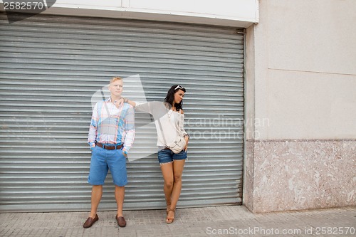 Image of Fashionable couple posing in front of a metal door