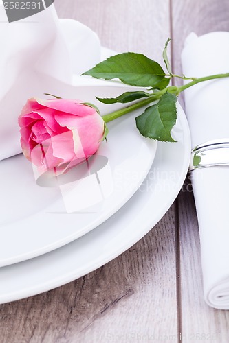 Image of Table setting with a single pink rose