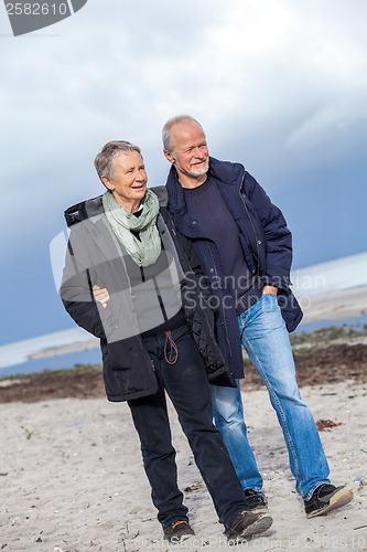 Image of happy elderly senior couple walking on beach