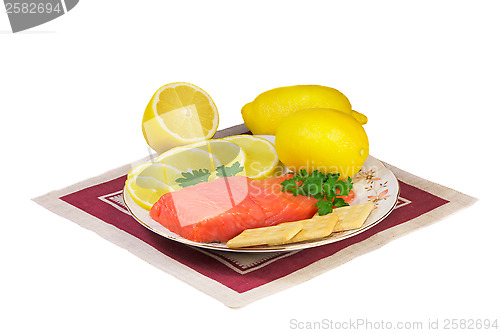 Image of Salmon fillet and lemons on a platter on a white background.