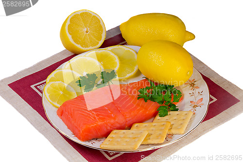 Image of Salmon fillet and lemons on a platter on a white background.