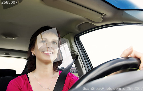Image of Smiling brunette woman driving car