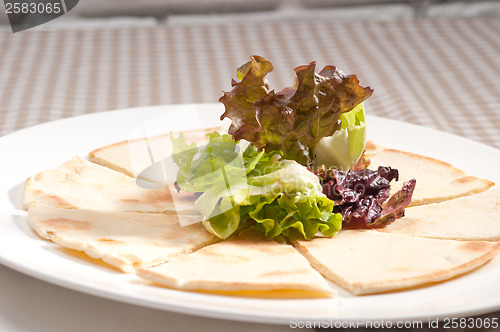 Image of garlic pita bread pizza with salad on top