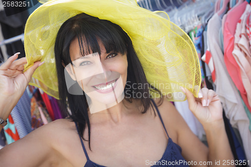 Image of Pretty Italian Woman Trying on Yellow Hat at Market