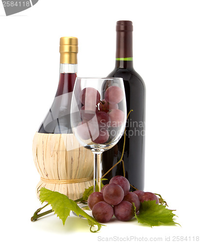 Image of wine glass full with grapes and two wine bottles 