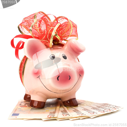 Image of Christmas deposit concept. Piggy bank with festive bow isolated 