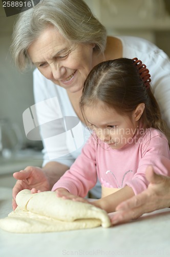 Image of Little girl kneading dough with grandmother