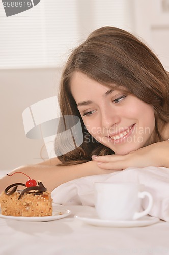 Image of woman lying in bed with cake and juice