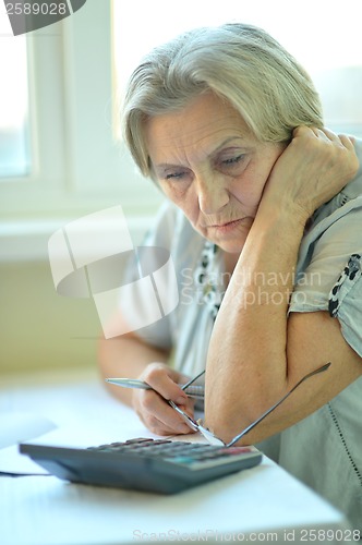 Image of Serious elderly woman with calculator
