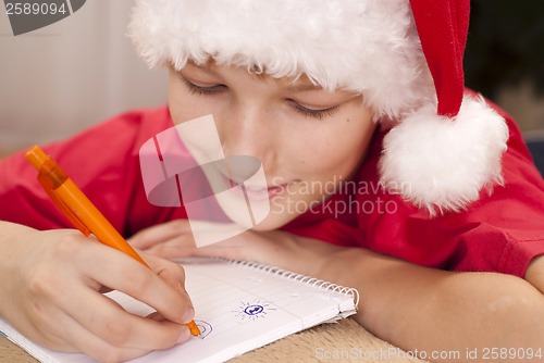 Image of Boy in santa hat writing