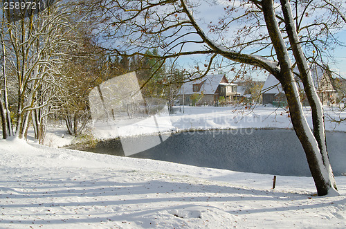 Image of Autumn landscape with snow by a pond in rural  