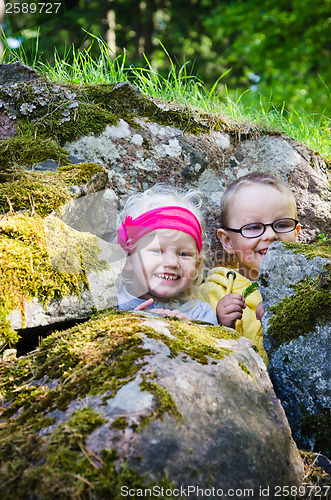 Image of Young children, the boy with the girl hid among the rocks