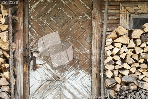 Image of old door, firewoods beside the wall
