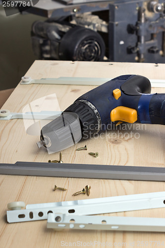 Image of Furniture parts and electric screwdriver on wooden table