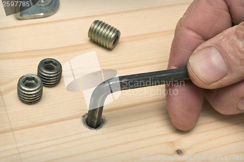 Image of Screwing furniture fasteners in a wooden new shield