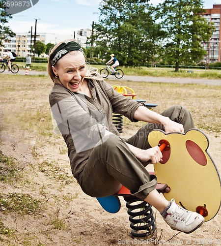 Image of Young woman swinging on a baby swing