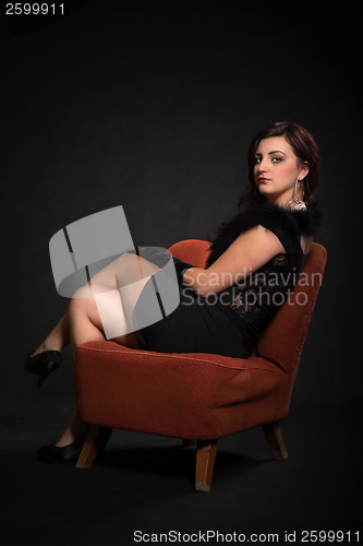 Image of Young woman in retro clothing on old orange chair