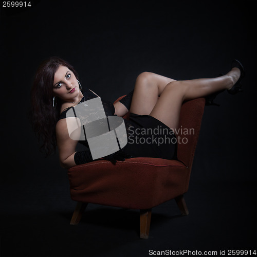 Image of Young woman in retro clothing on old orange chair