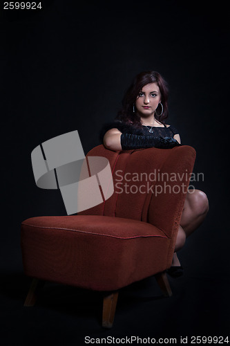 Image of Young woman in retro clothing on old orange chair