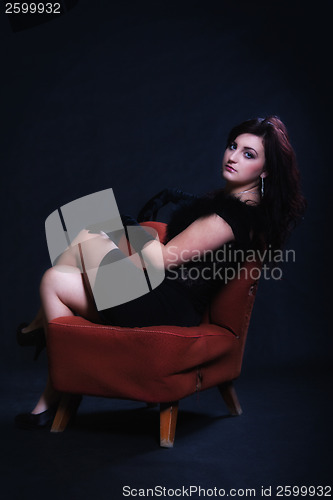 Image of Young woman in retro clothing on old orange chair