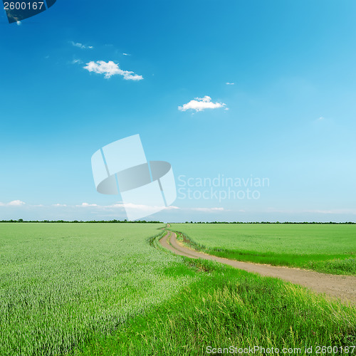 Image of road in green field under blue sky