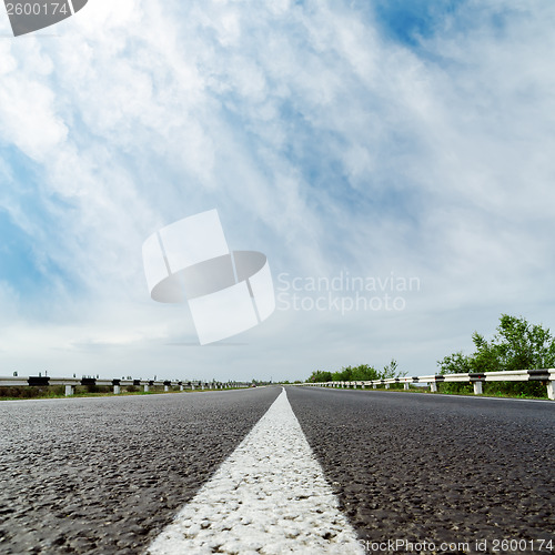 Image of white line on asphalt road and clouds over it