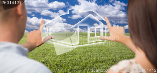 Image of Couple Framing Hands Around House Figure in Grass Field