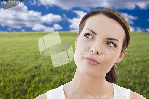 Image of Contemplative Woman in Grass Field Looking Up and Over