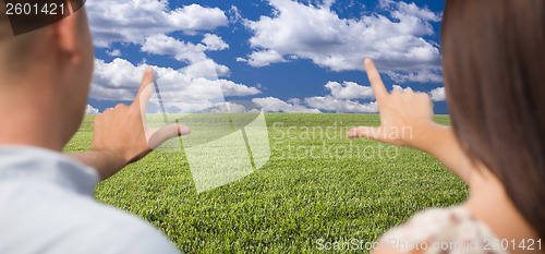 Image of Couple Framing Hands Around Space in Grass Field
