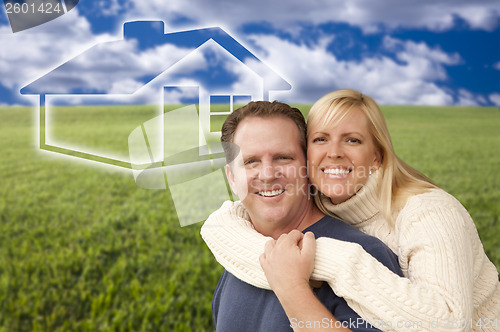 Image of Happy Couple Hugging in Grass Field with Ghosted House Behind