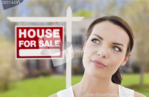 Image of Thinking Woman In Front of House and For Sale Sign