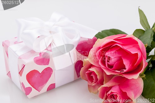 Image of Gift box with an empty tag, next to three roses