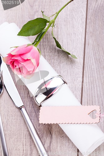 Image of Table setting with a single pink rose