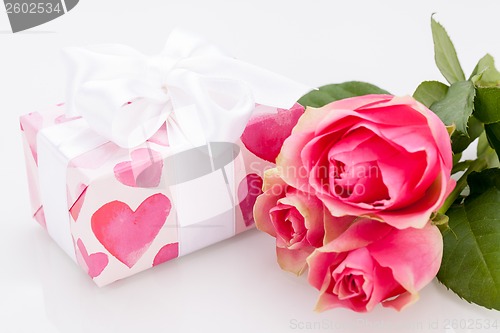 Image of Gift box with an empty tag, next to three roses