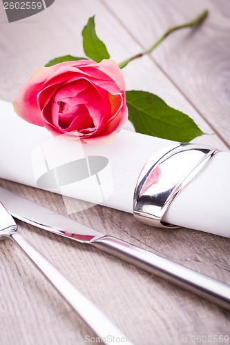 Image of Table setting with a single pink rose