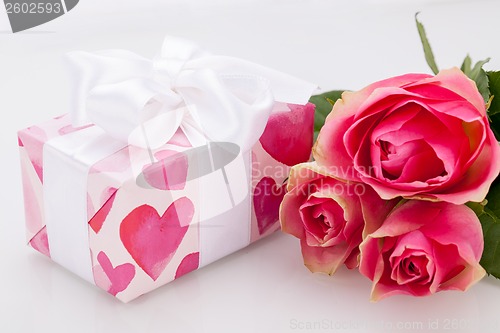 Image of Gift box with an empty tag, next to three roses