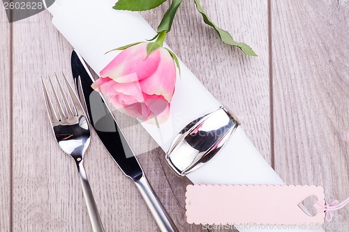 Image of Table setting with a single pink rose