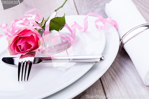 Image of Table setting with a single pink rose