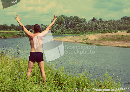 Image of man with hands up near river - vintage retro style
