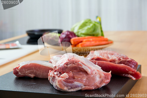 Image of Meat parts with vegetables at background