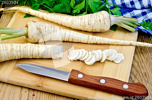 Image of Parsley root cut with a knife on board