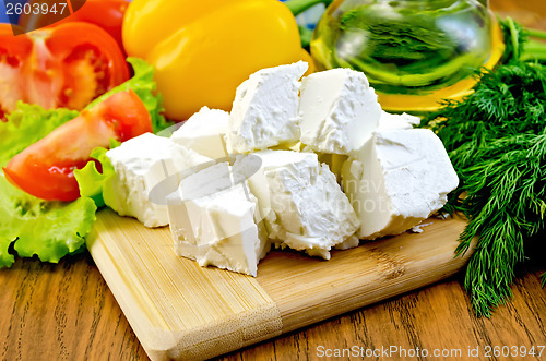 Image of Feta cheese on the board with vegetables and salad