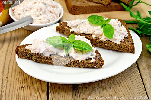 Image of Sandwiches with cream of salmon with basil on board
